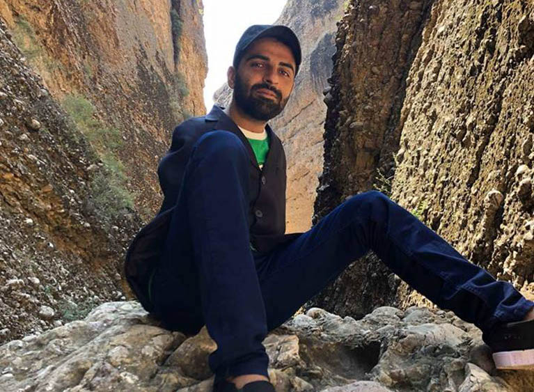 Photo of Abdul, who is sitting in a canyon.
