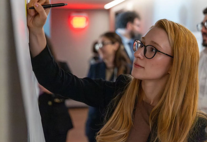 A woman writing on a whiteboard during a collaborative workshop.