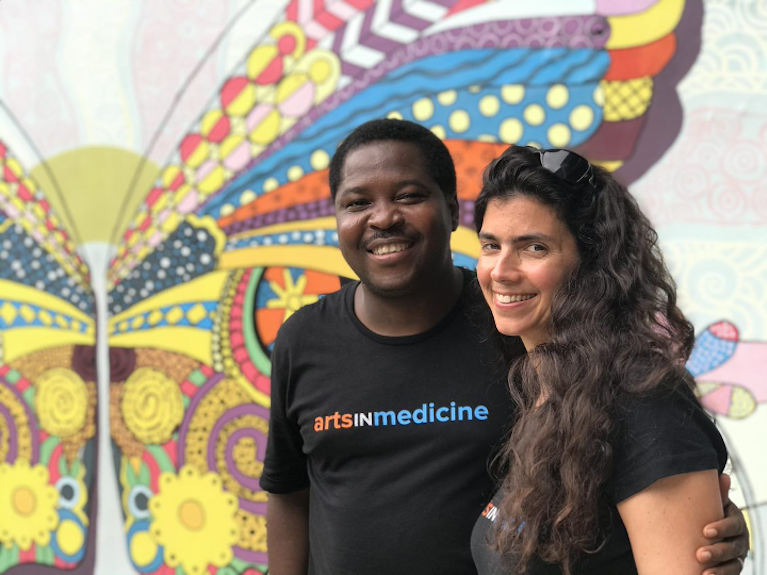 Two people in front of a mural depicting a butterfly.