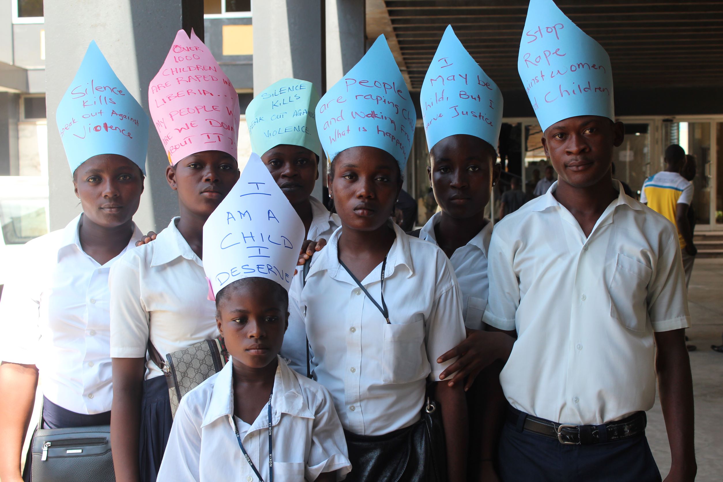 Photo of youth posing wearing hats with activist messages  