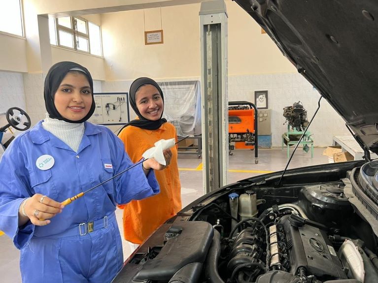 Two girls fixing a car