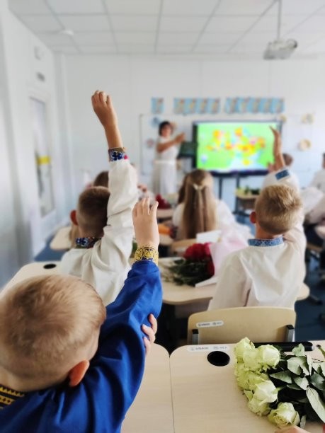 Young students raise their hand in a classroom 