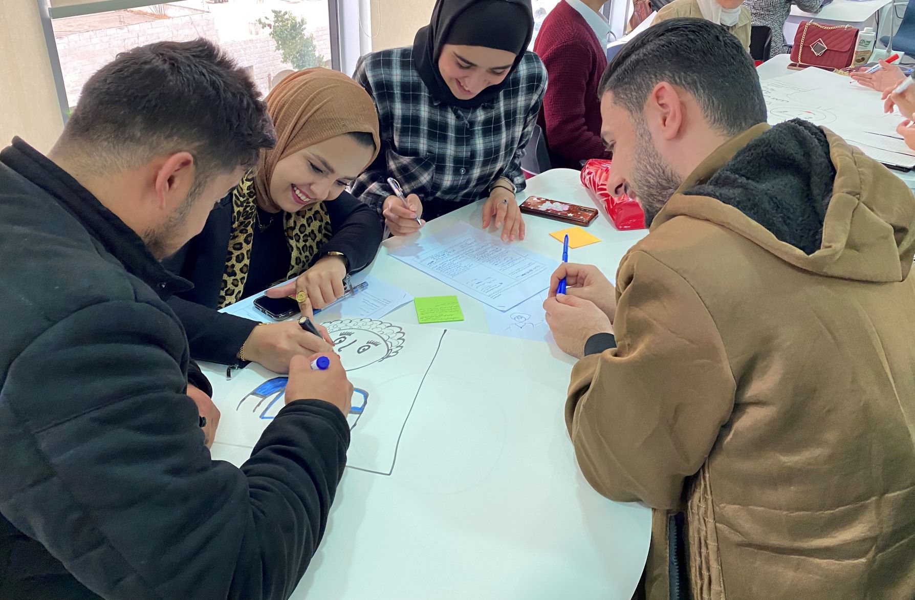 Group of four participants smiling and drawing on a table