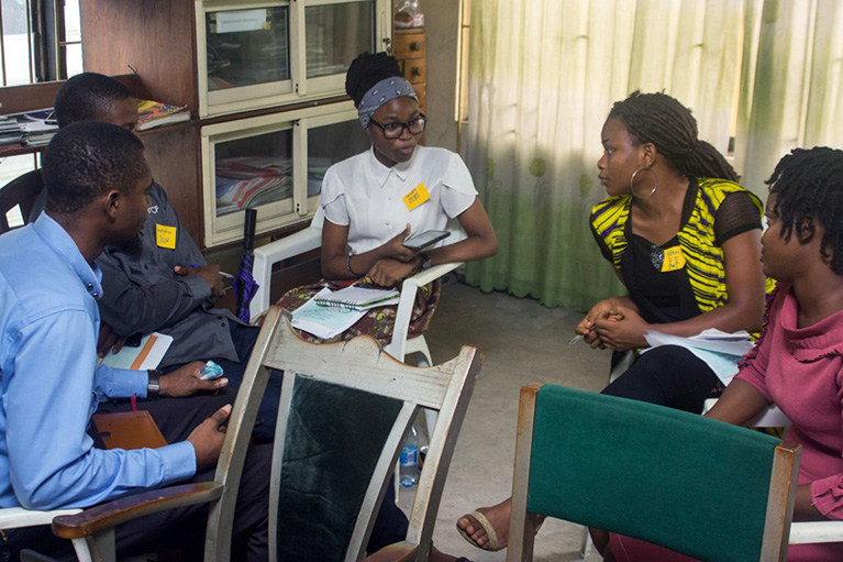 Photo of five people who are wearing nametags and sitting in a circle.