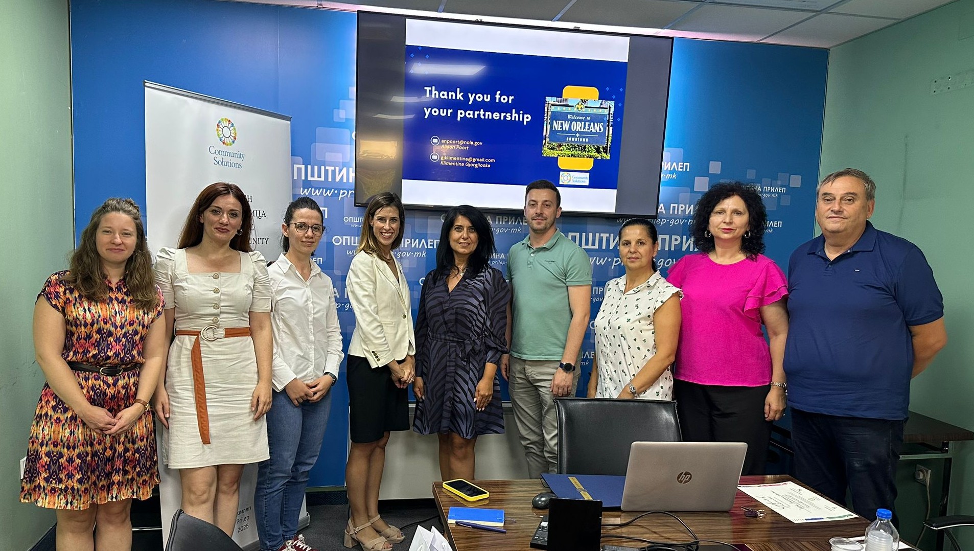 Photograph of eight people standing in a conference room.