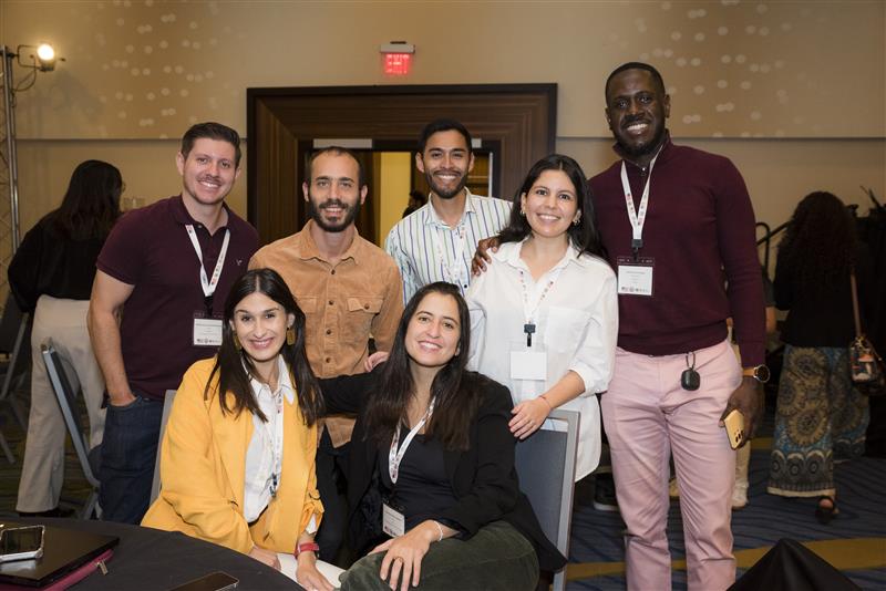 Group of 7 people posing and smiling in a conference room