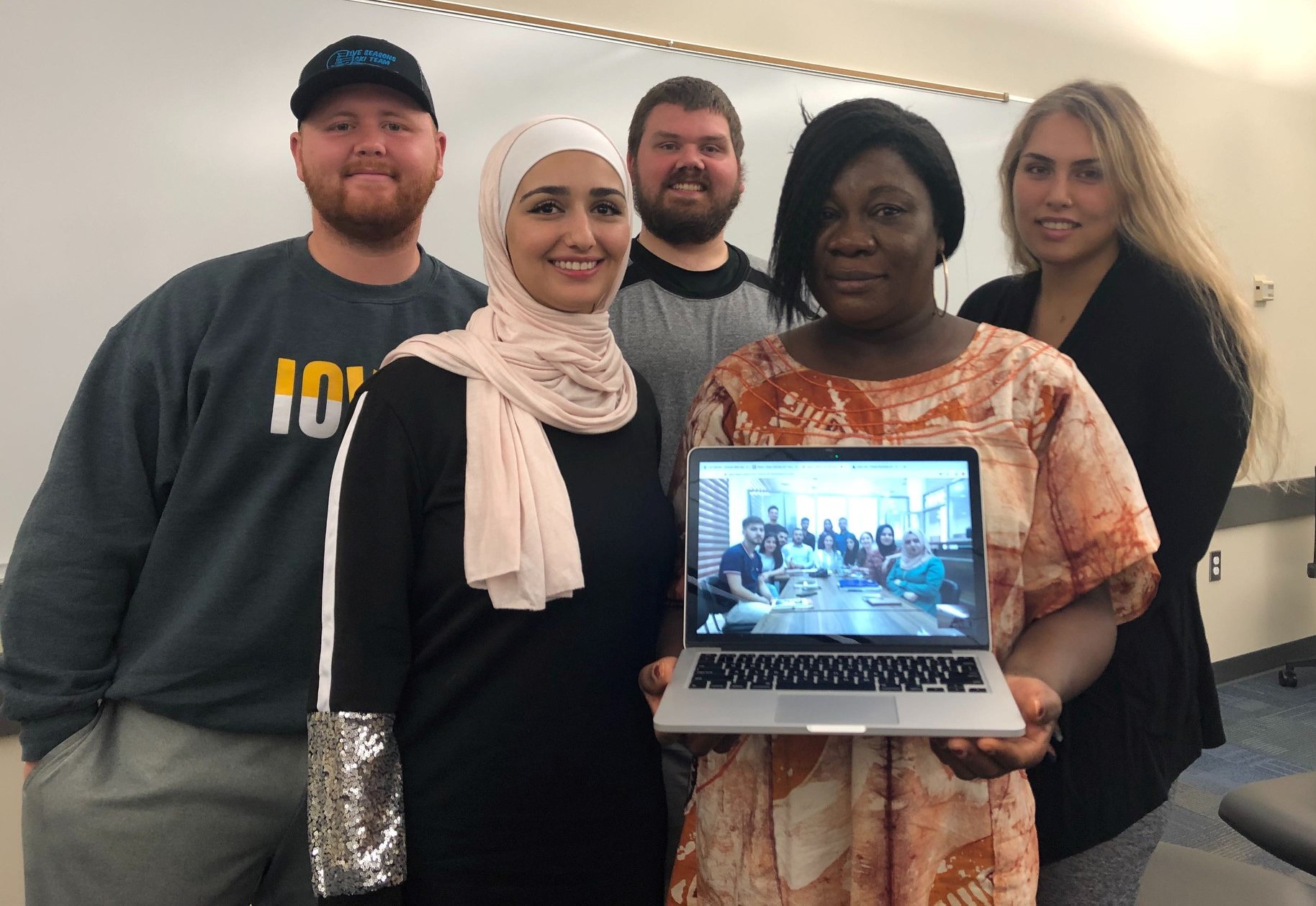 Photo of Global Solutions participants  holding a laptop with their virtual colleagues pictured .