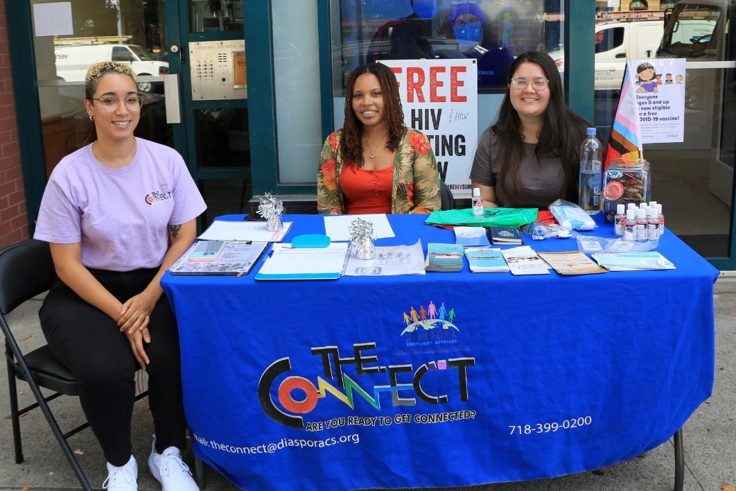 Three women sitting outside sharing information about their organization.
