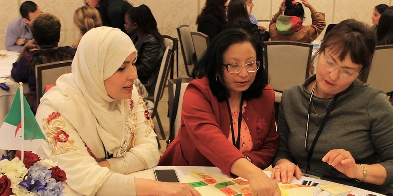 Photo of three female educators sitting at a conference table working on a project during a training.