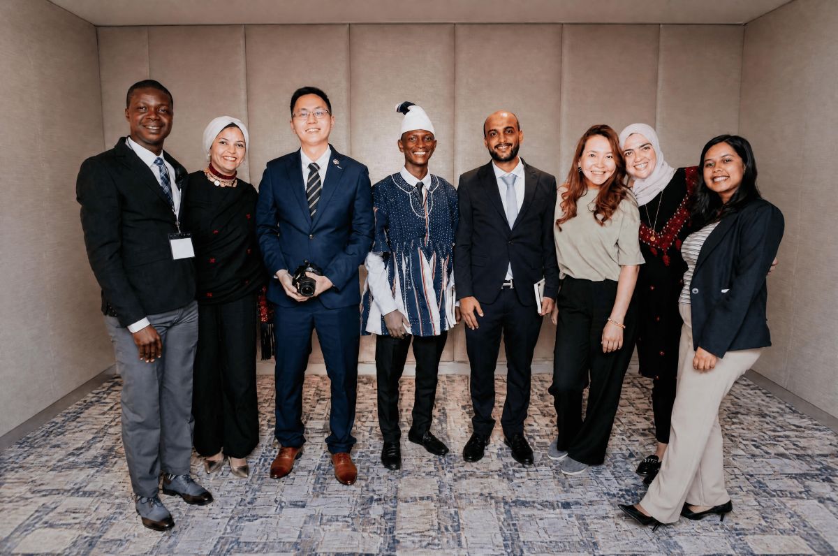 A group of 8 people posing together at an indoor professional event.
