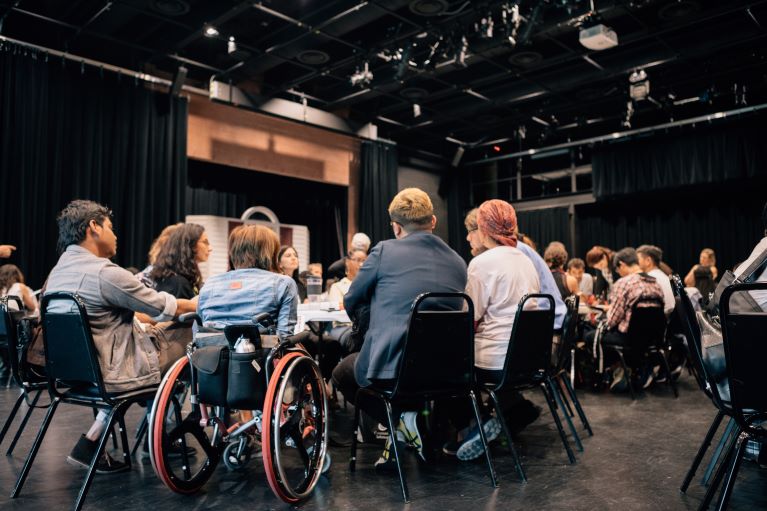 People gathered together sitting at a chair. One person is in a wheelchair.