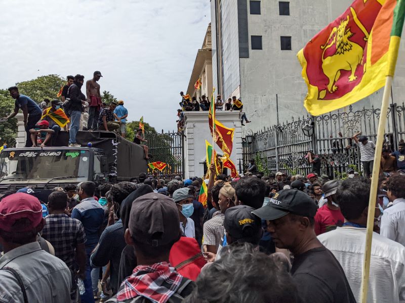 Image of protestors outside Presidential Palace, waving Sri Lankan flags 