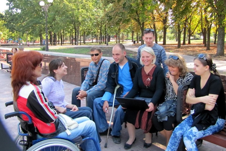 Group of patrons with disabilities sitting in a park having a discussion