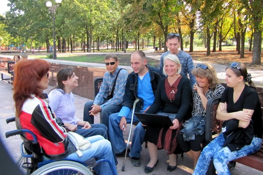 Group of patrons with disabilities sitting in a park having a discussion