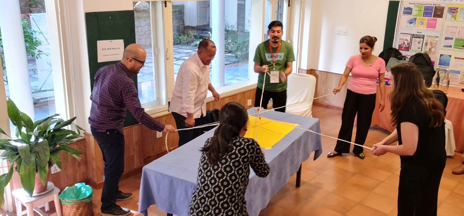 Group of people standing around a table holding string