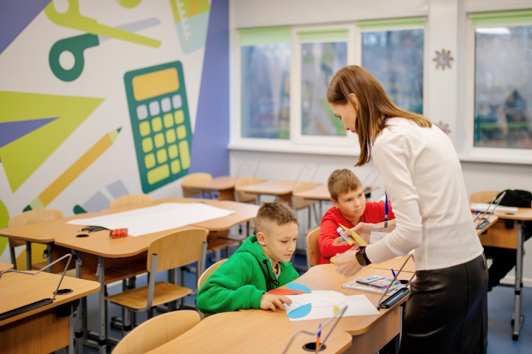 Educator speaks to young child in classroom