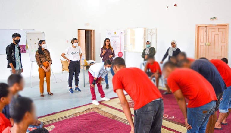 A group of people wearing masks in a large room