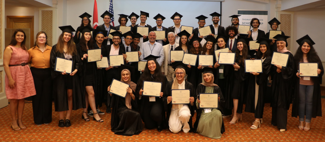 A group of students in graduation regalia holding their diplomas