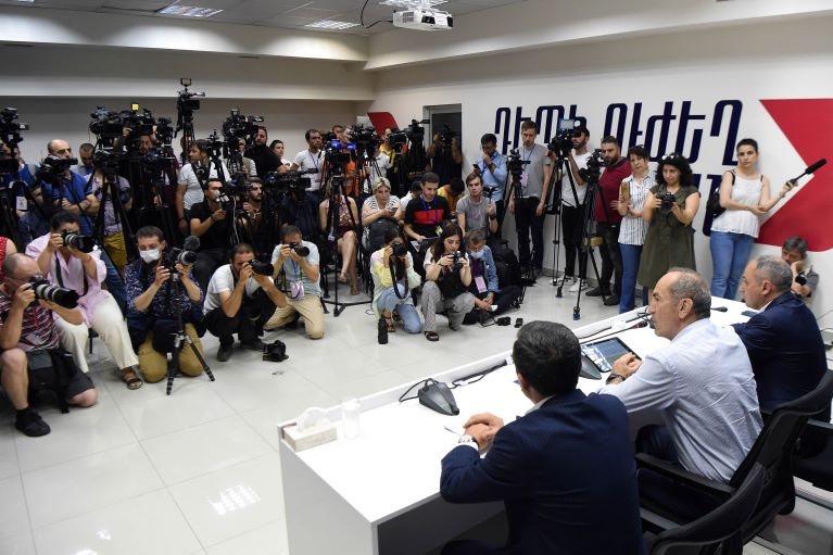 People at a desk facing a row of photographers  