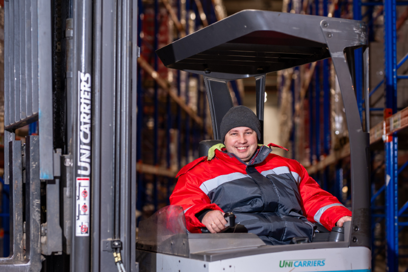 Yurii Dalyk smiling and operating a UniCarriers forklift inside a warehouse