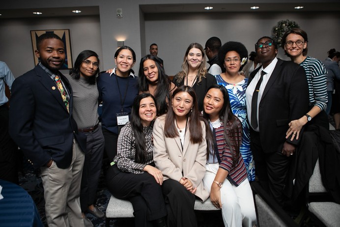 A group of 11 people posing together at an indoor professional event.