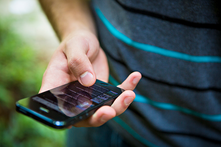 A person holding a mobile phone and browsing a newsfeed.