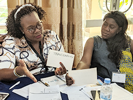 Two participants at a table. One person is talking about a card that says "Transparency."