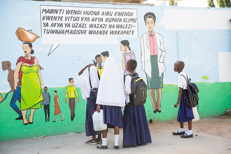 Students look at a mural that includes health messages.