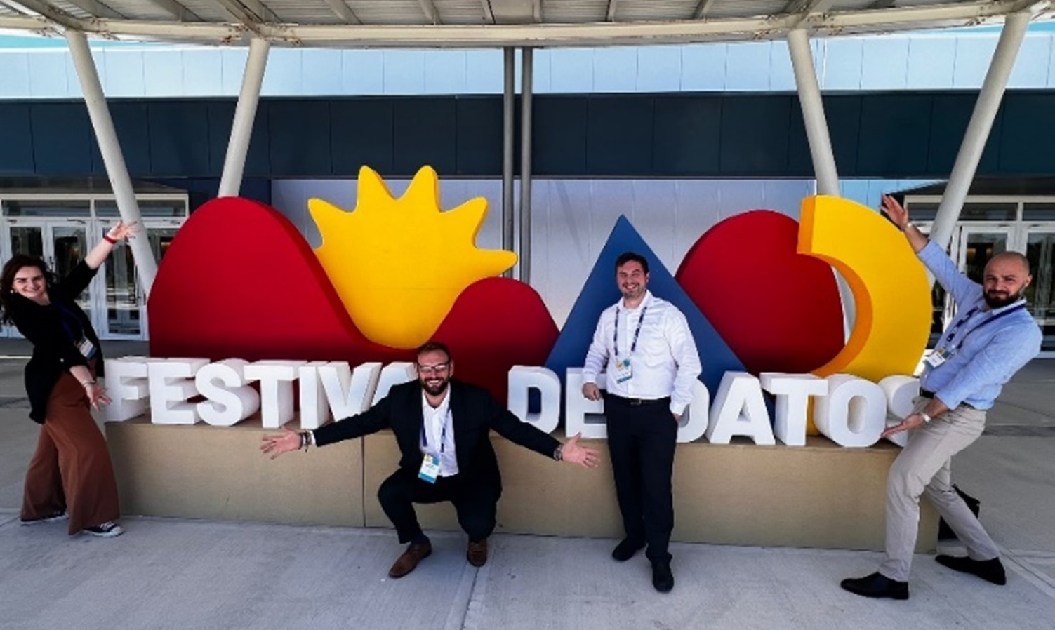 Three people smiling in front of a Festival De Datos sign