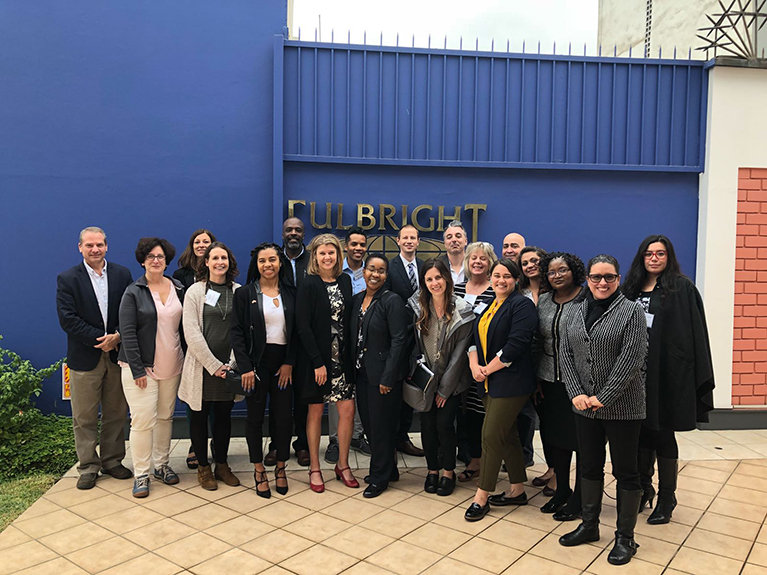 Teachers in front of wall with Fulbright logo