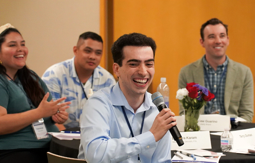 Photograph of a group discussion with one person holding a microphone and speaking.