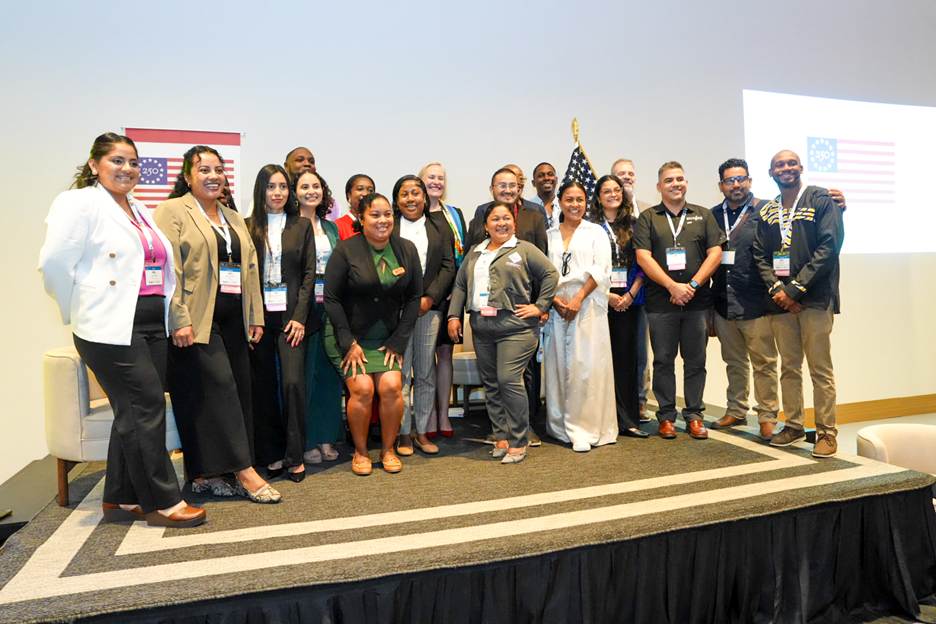 A group of 17 people standing on a stage, posing for a group photo at the YLAI event.
