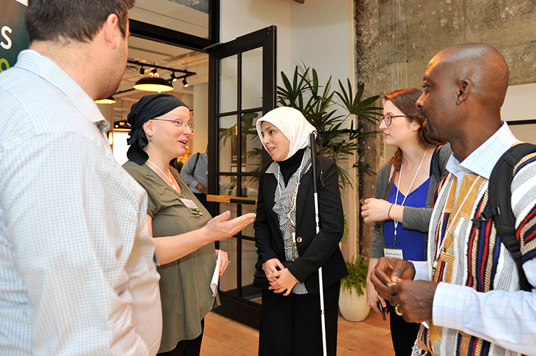 Five participants having an impromptu discussion in a hallway.