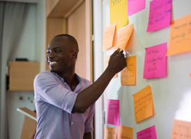 A participant rearranging sticky notes on a wall