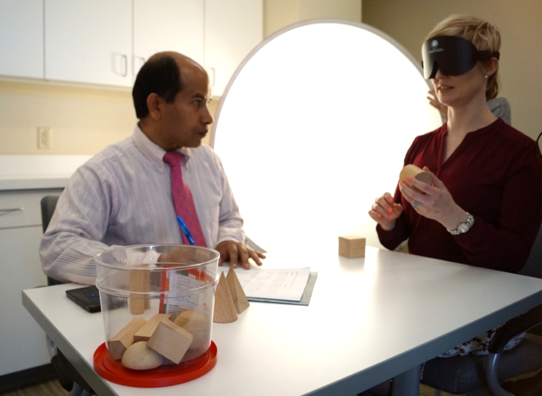 Photo of two people engaging in an assessment, a woman doing the test and a man taking notes