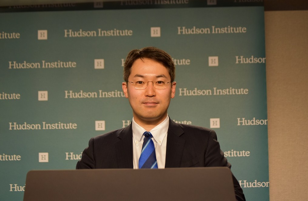 A person standing behind a podium with a Hudson Institute backdrop.