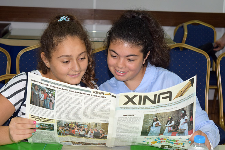 Two journalism students reading their story in the Xina newspaper