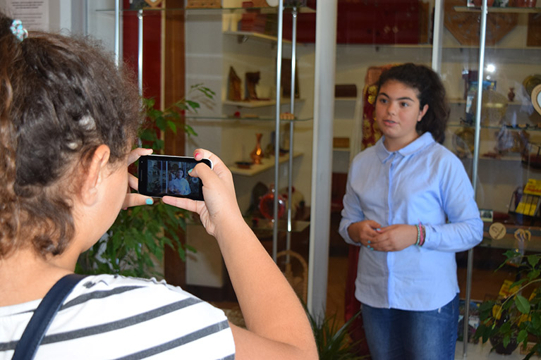 A journalism student recording another student with a smartphone