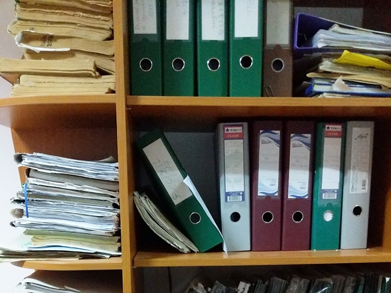 A bookcase full of papers and binders.