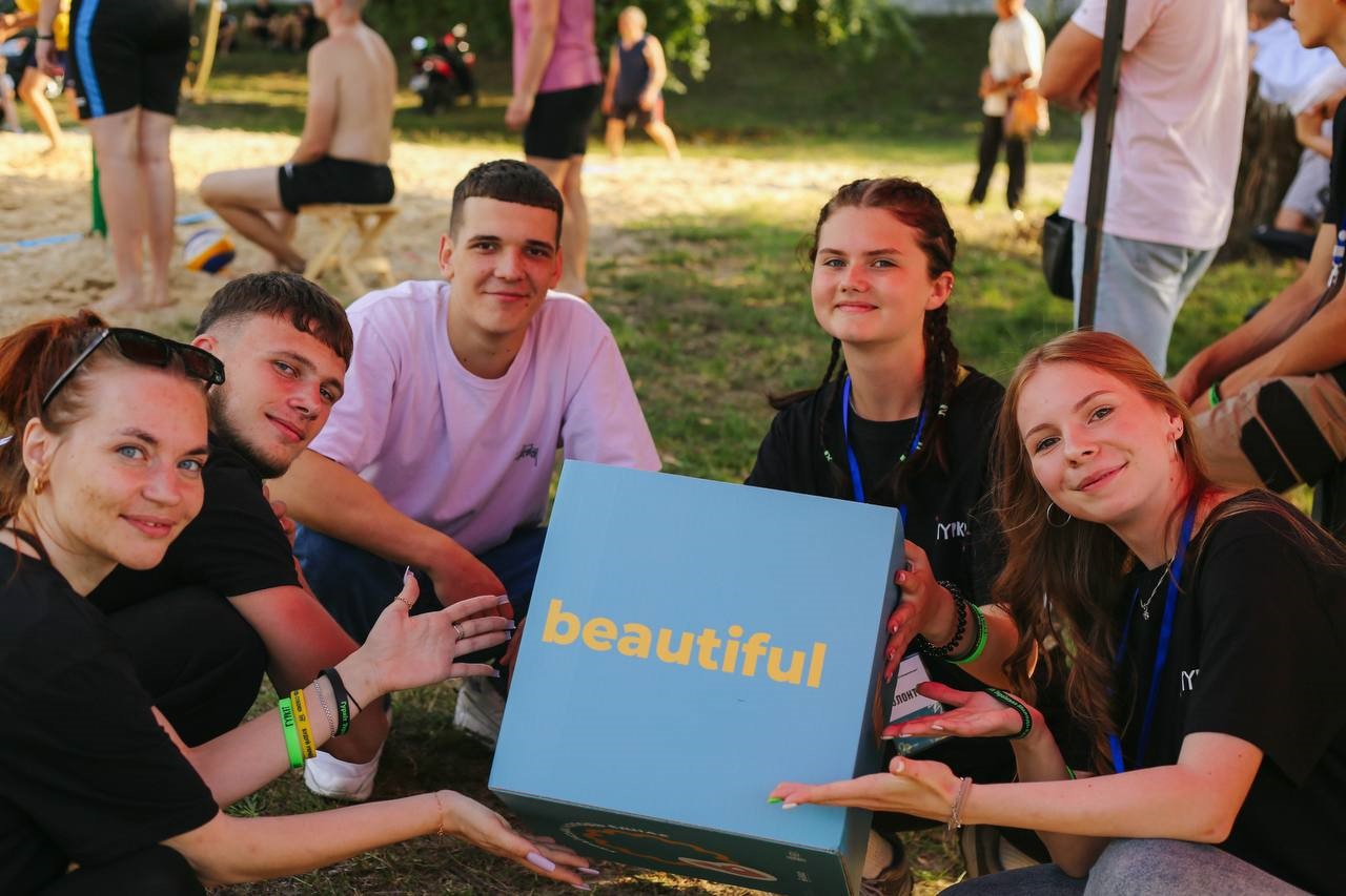 Group of young women and men hold a banner that says 'beautiful'. 