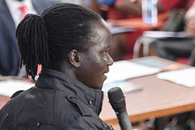 Photo of a young person speaking to an audience in an auditorium during a youth-led labor market assessment.