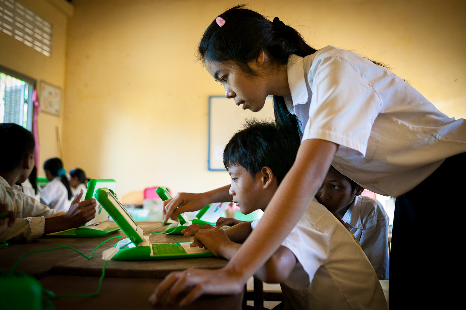 Teacher in a classroom helping students with computer skills