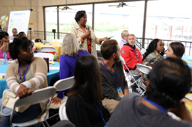 Young people sitting in a library listening to a person giving a presentation