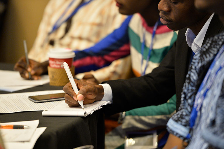 Program participants writing on notepads at a conference.