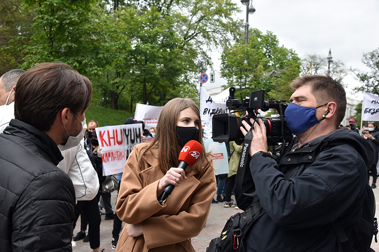 Two journalists interview a protester at a demonstration.