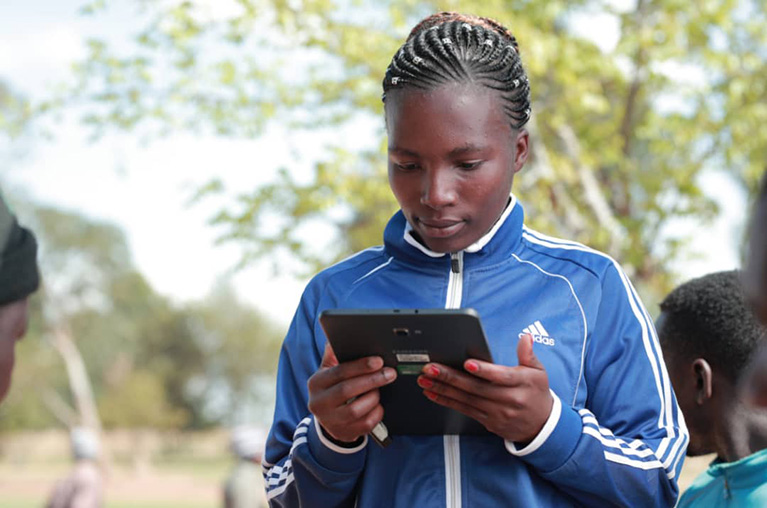 A person using a tablet while standing outside in Tanzania.