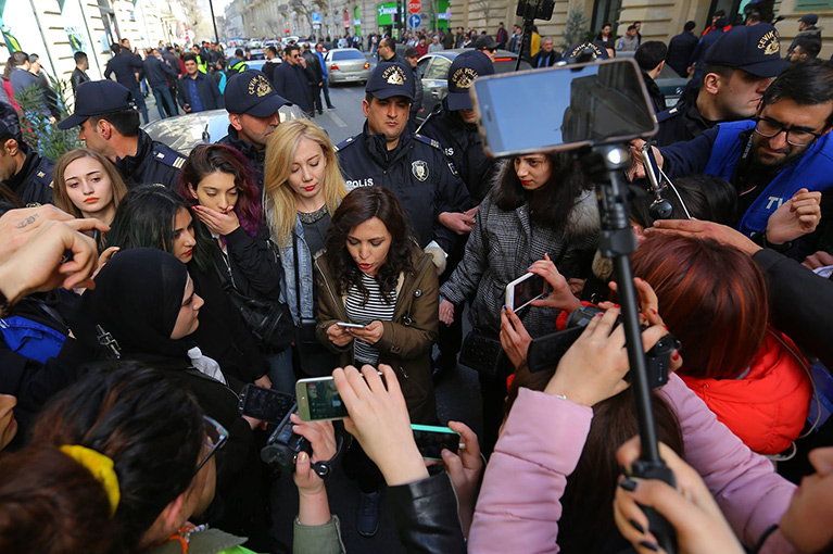 Reporters and residents record a spokesperson with their phones.