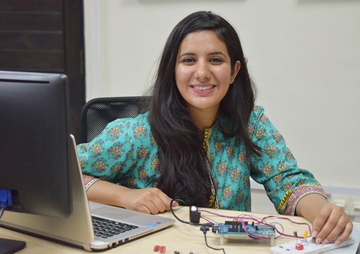 Malala sits at a desk in front of a laptop while conducting an experiment on the desk 