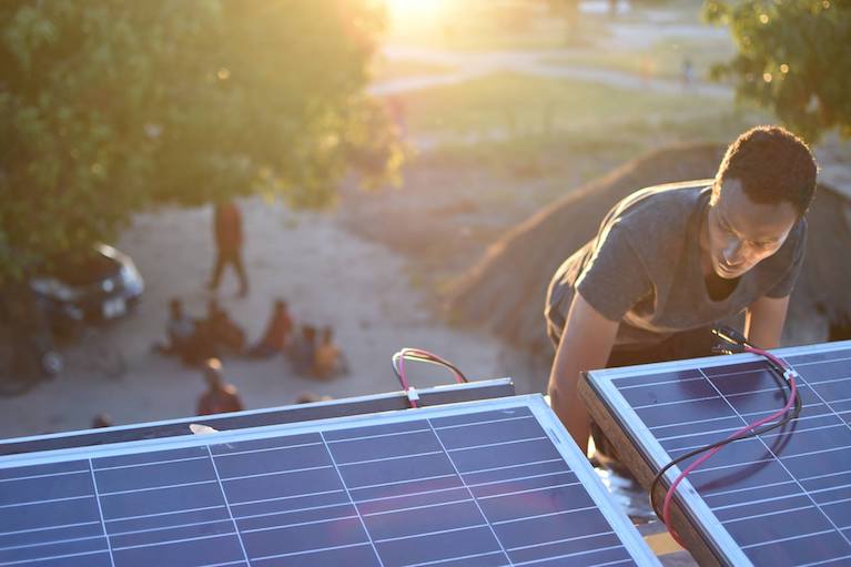 A man installs solar panels on a roof