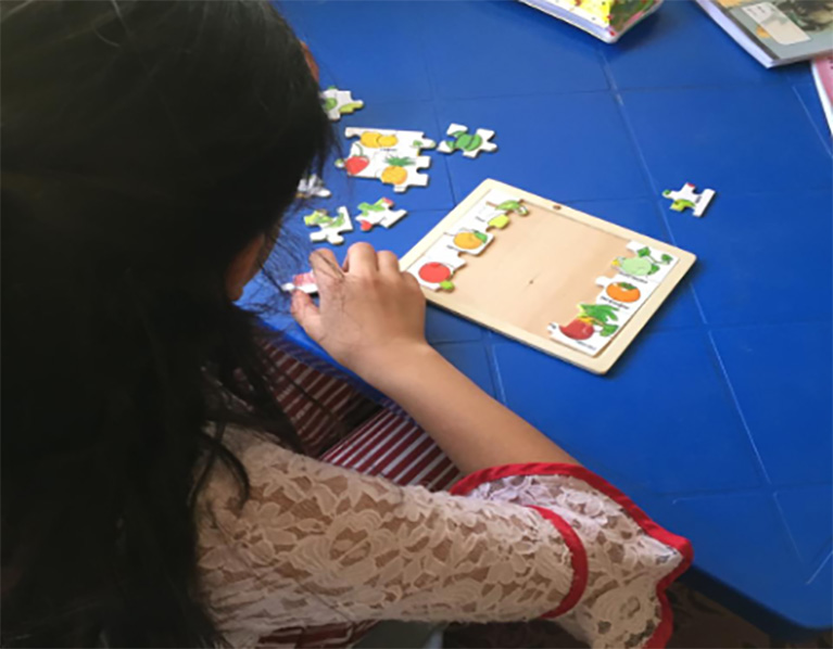 A child working on a puzzle at a table.